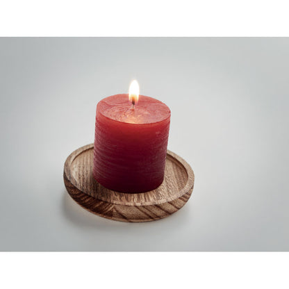 Vela encendida sobre porta velas de madera redondo fondo gris