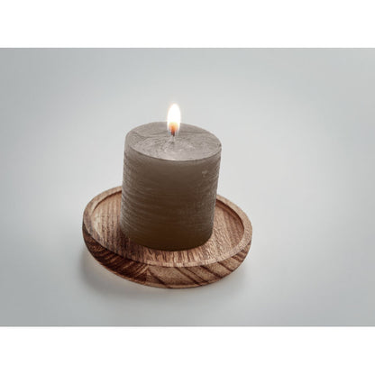 Vela encendida sobre porta velas de madera redondo fondo gris