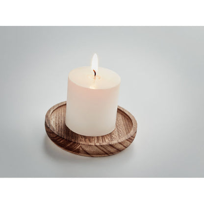 Vela encendida sobre porta velas de madera redondo fondo gris