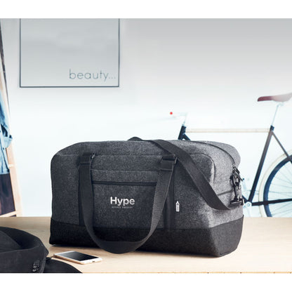 Bolsa de viaje de fieltro gris personalizada con logotipo sobre mesa de madera 