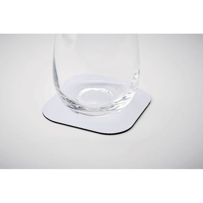 Vaso de cristal sobre posavasos blanco cuadrado