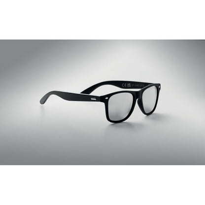 Gafa negra con lentes de espejo color gris sobre un fondo gris neutro