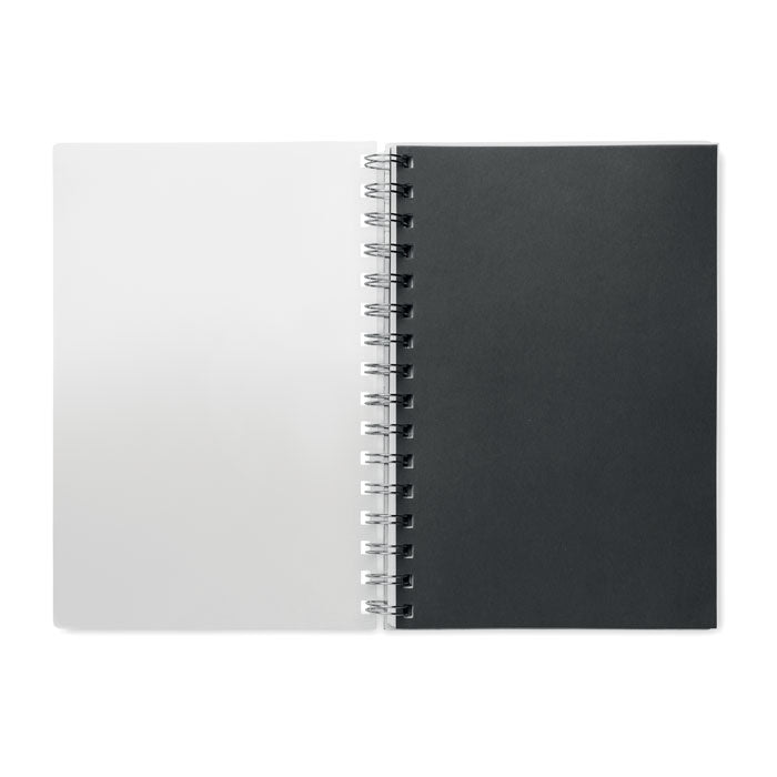Interior de libreta A5, con hojas blancas a la izquierda y papel negro a la derecha, anillada con espiral.