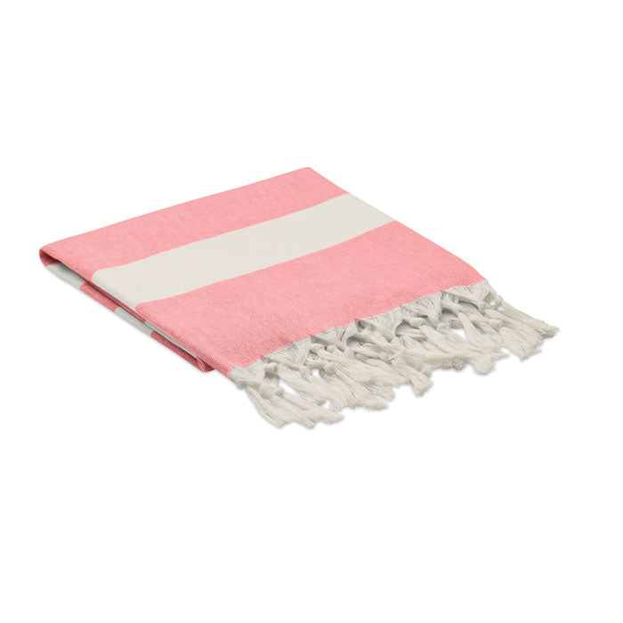 Toalla de playa rosa con franjas blancas y flecos, ideal para días de sol y relax, diseño en tejido reciclado.
