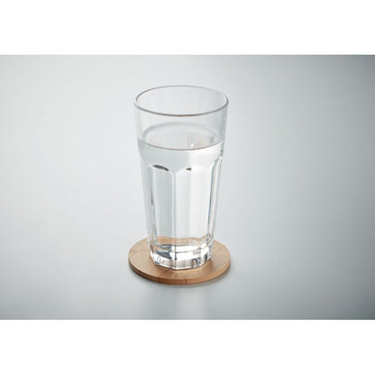 vaso de cristal alto con agua sobre posavasos de bambú