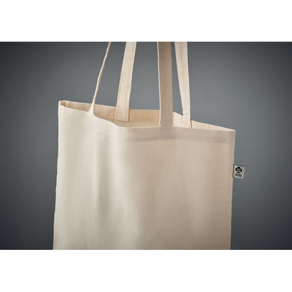 Detalle de parte superior de bolsa de algodón de asas largas con etiqueta de algodón orgánico cosida en el lateral