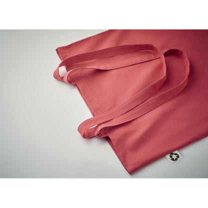 Detalle de asas largas y etiqueta de tejido reciclado en tote bag roja