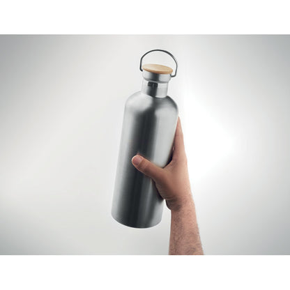 Mano sujetando botella plateada con asa