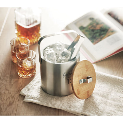 Cubitera llena de hielo sobre una mesa con vasos y botellas de whisky