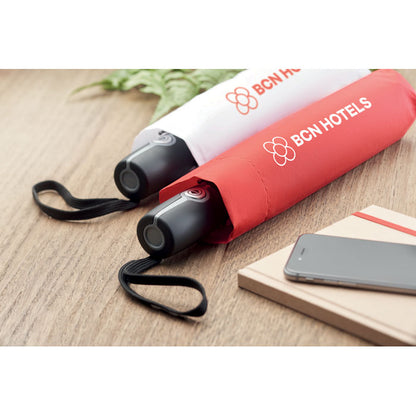 Paraguas blanco y un paraguas rojo plegados y personalizados con un logotipo en la funda sobre una mesa de madera