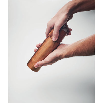 Manos utilizando un molinillo de pimienta de madera