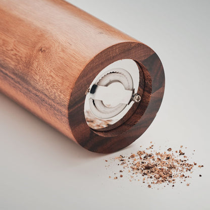 Manos utilizando un molinillo de pimienta de madera