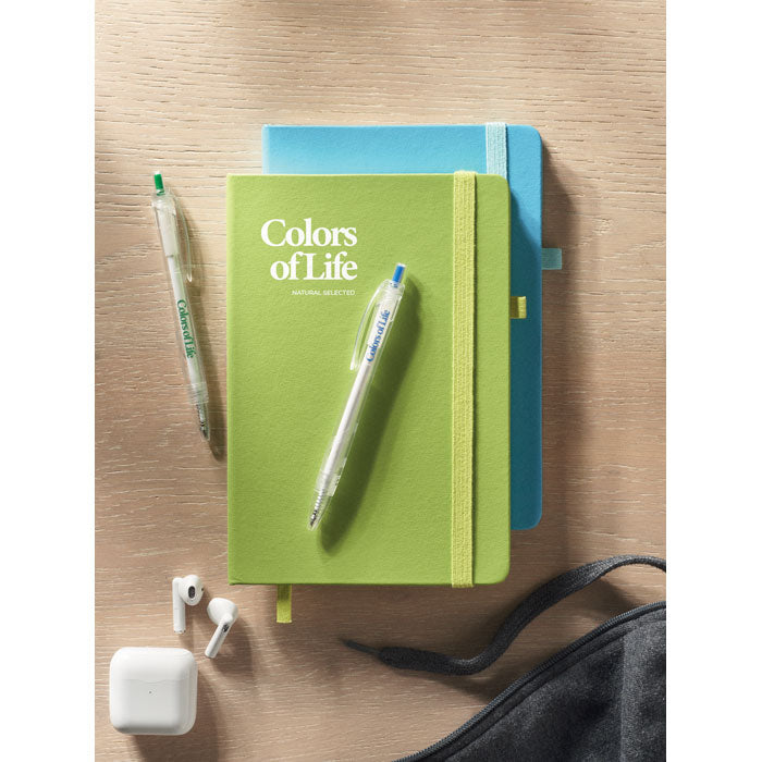 Vista superior de libretas de colores verde y azul, con bolígrafos y auriculares inalámbricos sobre una mesa de madera.