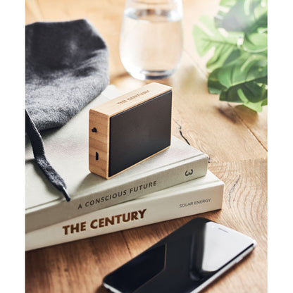 Altavoz inalámbrico sobre varios libros encima de una mesa de madera