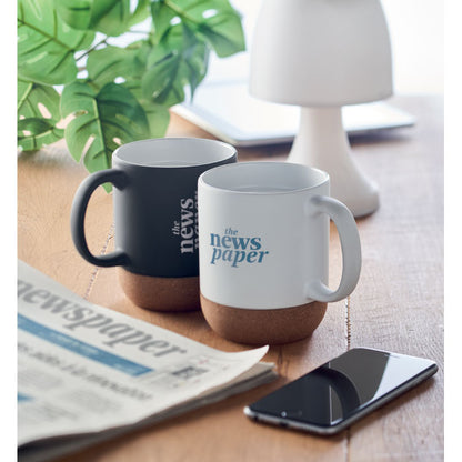 Pareja de tazas de cerámica blanca y negra con base inferior de corcho personalizadas con base de corcho en una mesa de oficina