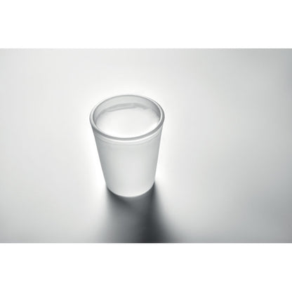 Vaso de chupito con licor sobre superficie gris neutro