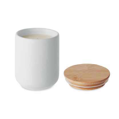 Vela en tarro de cerámica blanca con tapa de madera al lado