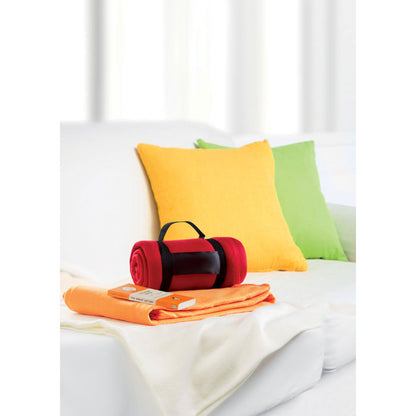 Manta roja y naranja sobre un sillón y al lado de un par de cojines de colores