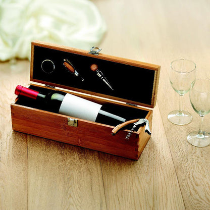 Collar de botella, vertedor, tapón y sacacorchos en caja de madera con botella de vino sobre mesa de madera