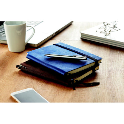 Mesa de madera con 2 libretas, móvil, taza y portátil