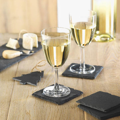 Copas de vino sobre posavasos de pizarra negros en mesa de comedor
