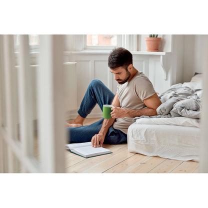 hombre bebiendo de una taza verde de cerámica en una habitación 