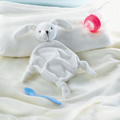 Doudou conejito en una cuna de bebé al lado de un chupete y un biberón