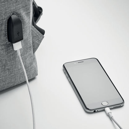 Móvil cargando a través de cable USB conectado a la mochila beige