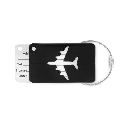 Identificador de maleta de aluminio negro con figura de avión en la parte superior y etiqueta para rellenar datos personales