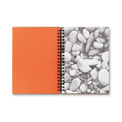 Libreta con espiral abierta. El interior de la portada es de color naranja y la primera hoja tiene una foto de piedras