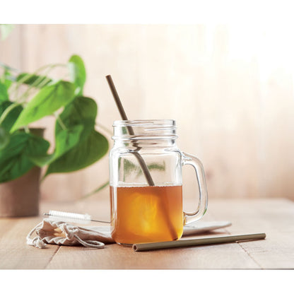 Infusión en jarrita de cristal con pajita sobre mesa de madera