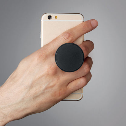 Mano sujetando teléfono con soporte redondo negro entre los dedos