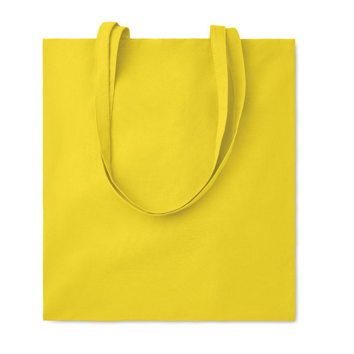 Bolsa de algodón amarilla con asas largas, material de 180 gr/m², vista frontal.
