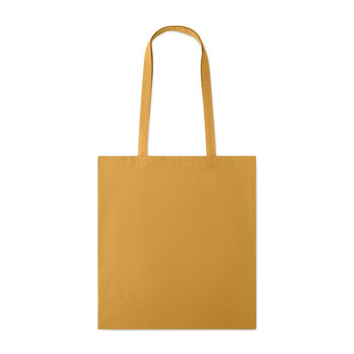 Bolsa de algodón de color mostaza con asas largas, vista frontal y fondo liso.