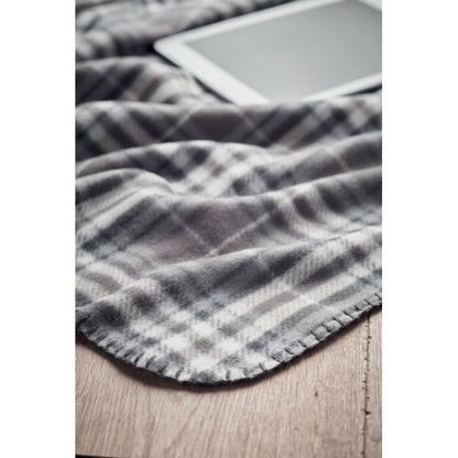 destalle de borde de manta de cuadros gris sobre madera