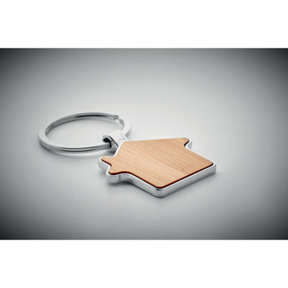 Porta llaves de madera con forma de casa sobre fondo gris