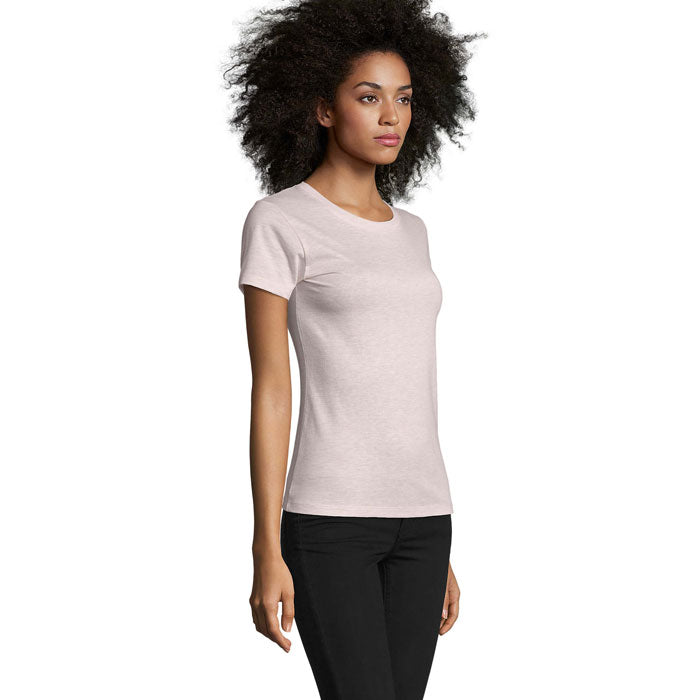 Mujer con camiseta entallada de cuello redondo en color rosa claro, vista lateral. Fabricada en 100% algodón, ajuste cómodo.