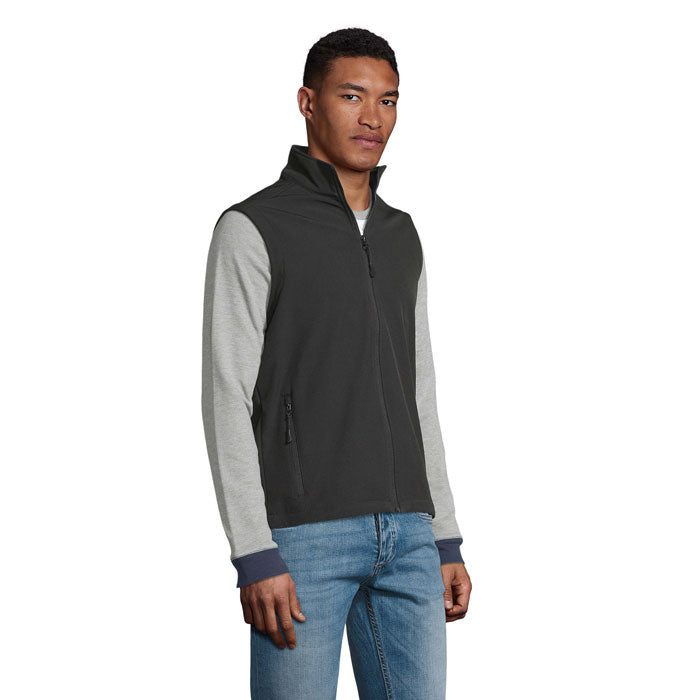 Vista lateral de un chaleco softshell en color negro, con detalles en gris, ideal para hombre, destacando su diseño moderno y funcional.
