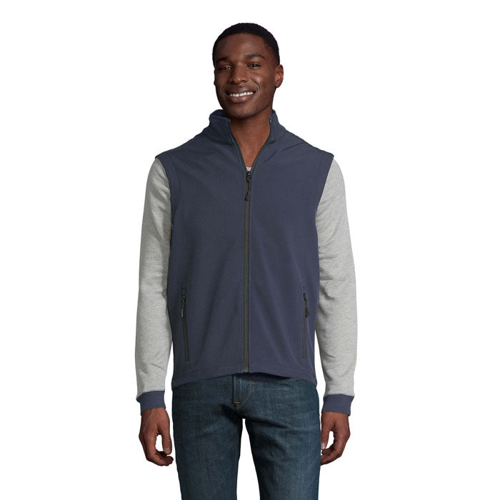 Chaleco softshell para hombre en color gris y azul, con capucha y bolsillos con cremallera. Modelo luciendo RACE BW MEN.