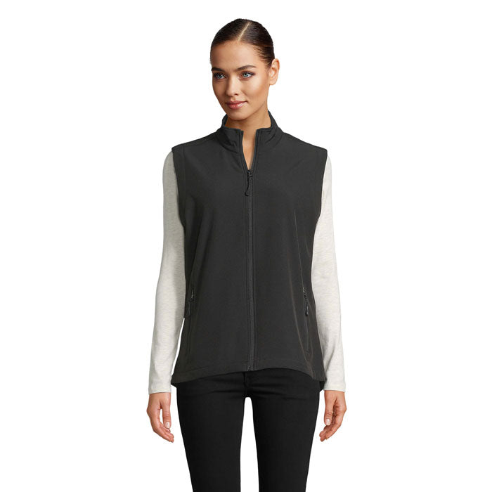Vista frontal de chaleco softshell negro para mujer, con cremallera y dos bolsillos laterales.