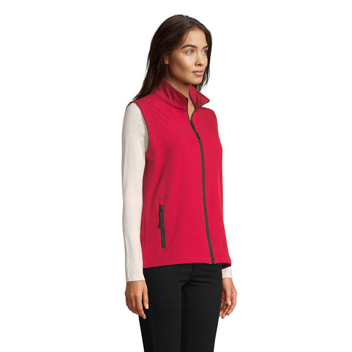 Modelo con chaleco softshell rojo sin mangas, detalle de cremallera y bolsillos laterales, parte frontal.