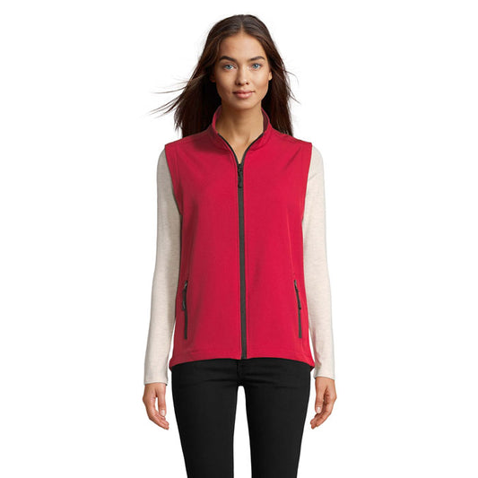 Mujer vistiendo chaleco softshell rojo con cremallera y bolsillos, ideal para actividades al aire libre.
