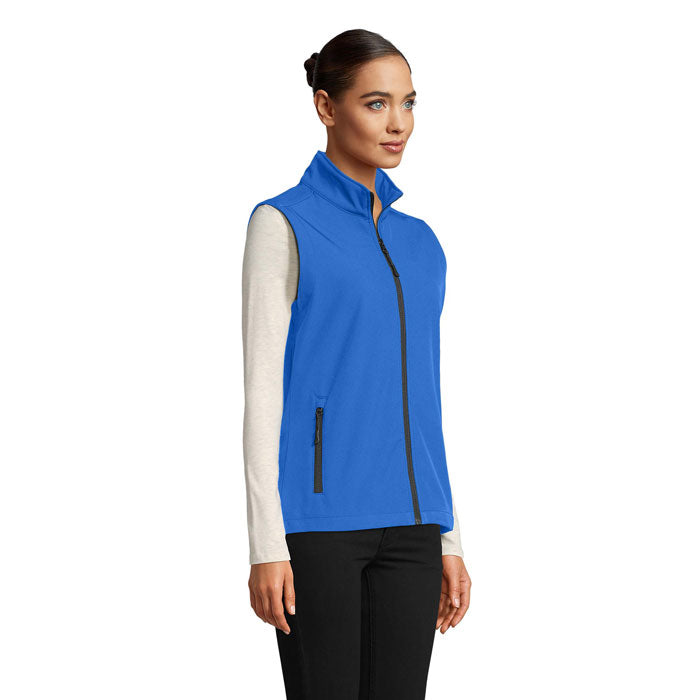 Vista lateral de chaleco softshell azul para mujer, con cremallera y bolsillos, ideal para uso diario.