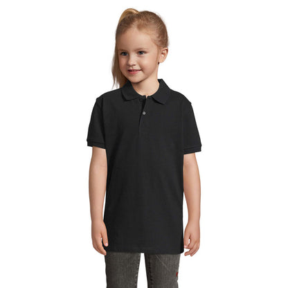 Modelo infantil femenina vistiendo polo negro de corte recto y manga corta.
