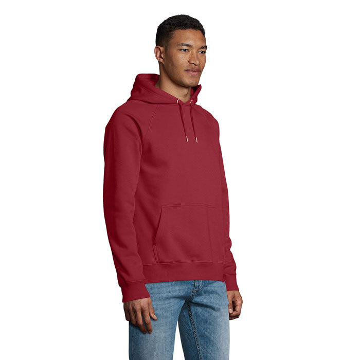 Vista lateral de un hombre usando una sudadera con capucha roja, fabricada en 80% algodón orgánico y 20% poliéster reciclado.