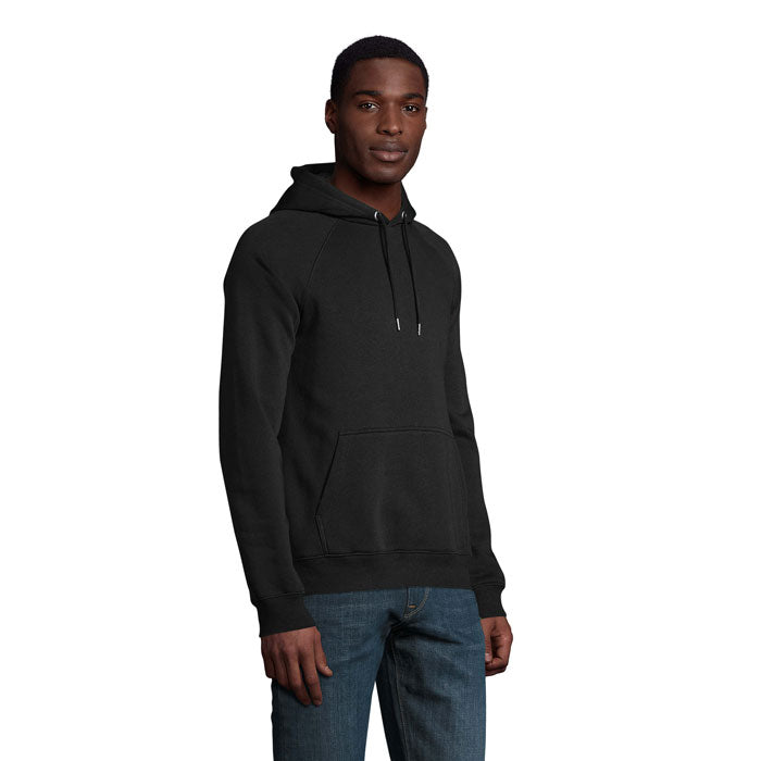 Modelo masculino vistiendo una sudadera negra de capucha, hecha de algodón orgánico y poliéster reciclado, ideal para un look casual.
