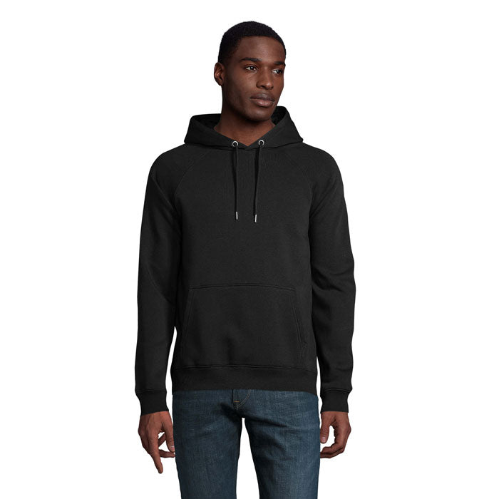 Modelo masculino usando sudadera negra con capucha, confeccionada en algodón orgánico y poliéster reciclado, diseño moderno.