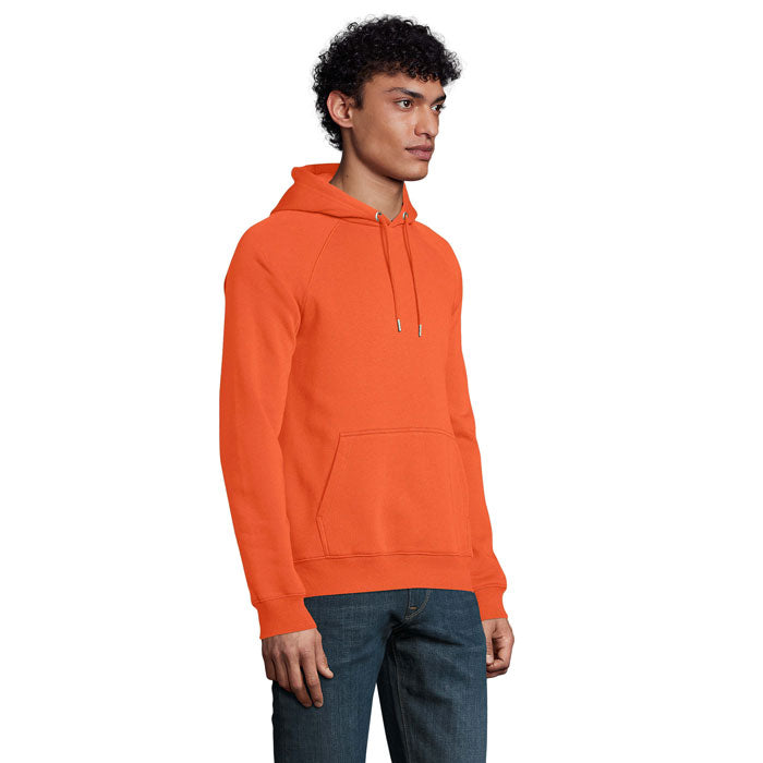 Vista lateral de sudadera con capucha naranja, 80% algodón orgánico, combinada con jeans, mostrando diseño unisex.