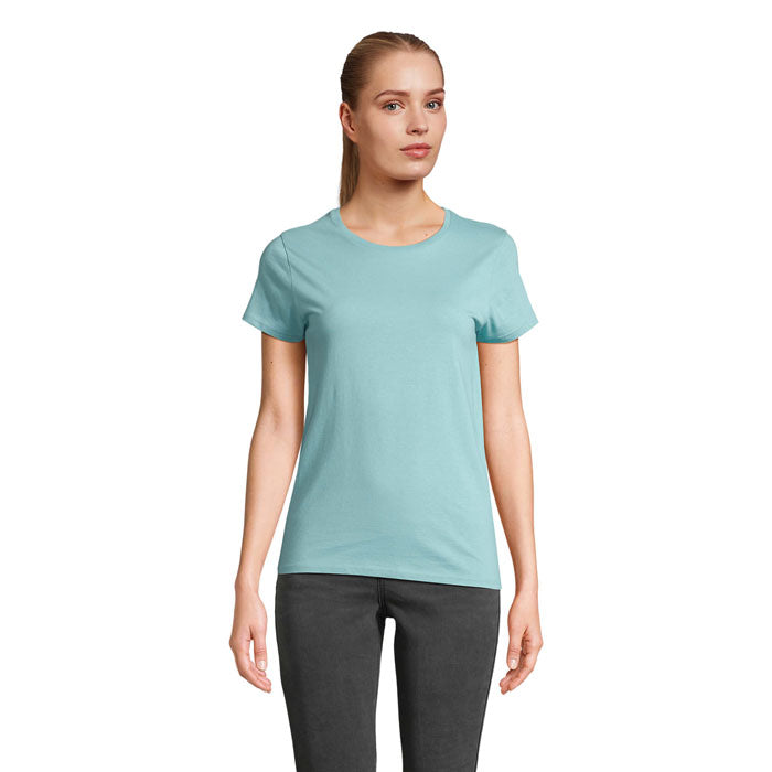 Modelo en camiseta azul claro ajustada de algodón orgánico, vista frontal, combinada con pantalones oscuros.