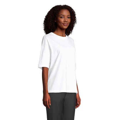Modelo femenina de perfil con camiseta blanca oversize y pantalón negro.